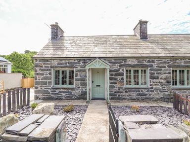 Stone cottage exterior with slate roof and green door and windows at Ffrwdd Galed Uchaf in Tregarth