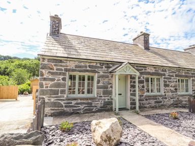 A stone cottage with a slate roof and three windows with a small porch at Ffrwdd Galed Uchaf in Tregarth