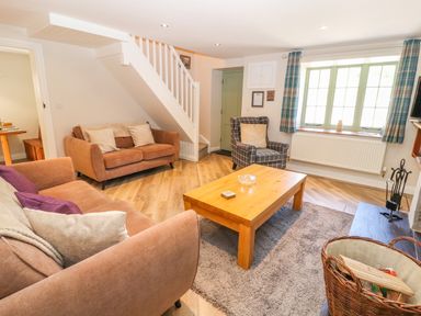 A living room with two sofas an armchair a wooden coffee table and a window with curtains at Ffrwdd Galed Uchaf in Tregarth