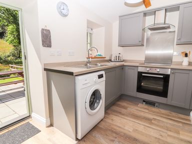 A kitchen with a washing machine a sink an oven and cabinets at Ffrwdd Galed Uchaf in Tregarth