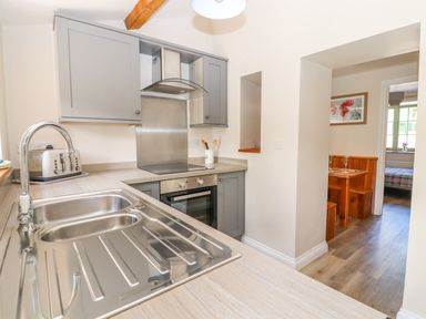 A kitchen with a stainless steel sink a toaster a stove oven and grey cabinets at Ffrwdd Galed Uchaf in Tregarth
