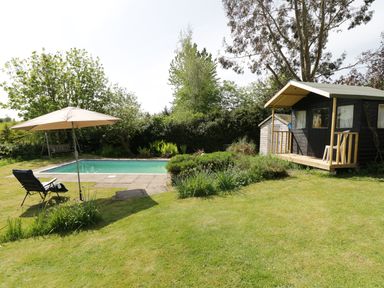 A garden with a small pool a sun lounger with umbrella and a wooden cabin at Rhydygaled in Llanrhaeadr-Ym-Mochnant
