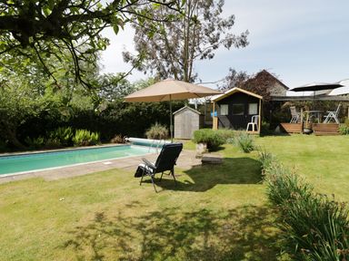 A garden with a swimming pool lawn chairs umbrellas storage sheds and a patio area at Rhydygaled in Llanrhaeadr-Ym-Mochnant