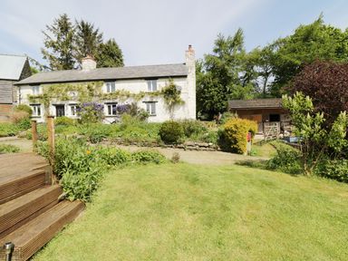 A stone cottage with garden and wooden steps in front at Rhydygaled in Llanrhaeadr-Ym-Mochnant