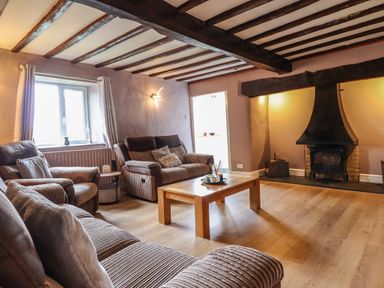 A living room with sofas a wooden coffee table and a fireplace at Rhydygaled in Llanrhaeadr-Ym-Mochnant