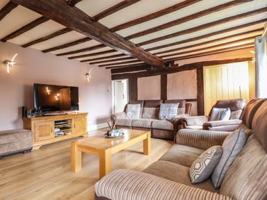 A living room with wooden beams on the ceiling sofas a wooden coffee table and a television on a wooden stand at Rhydygaled in Llanrhaeadr-Ym-Mochnant