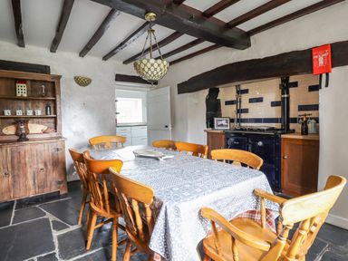 A dining room with wooden chairs and a table covered with a patterned tablecloth at Rhydygaled in Llanrhaeadr-Ym-Mochnant