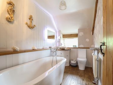 A bathroom with a bathtub toilet sink and a window at Rhydygaled in Llanrhaeadr-Ym-Mochnant