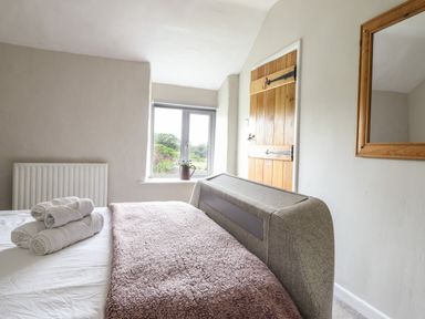 A bedroom with a bed covered with towels and a blanket next to a window and wooden door at Rhydygaled in Llanrhaeadr-Ym-Mochnant
