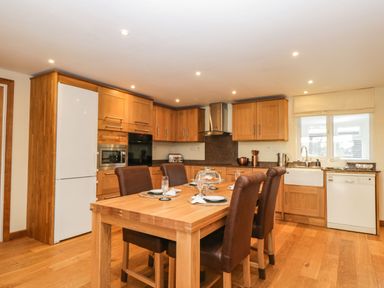 A kitchen with wooden cabinets and a wooden dining table with four brown chairs at The Annex in Royal Wootton Bassett