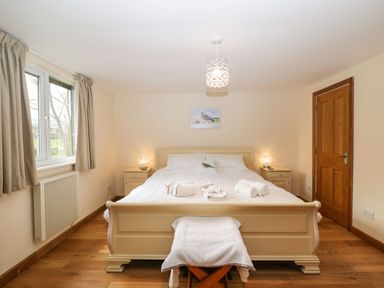 A bedroom with a bed flanked by two bedside tables with lamps and a door on the right at The Annex in Royal Wootton Bassett