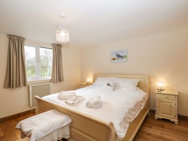 A bedroom with a double bed bedside tables lamps and a window with curtains at The Annex in Royal Wootton Bassett