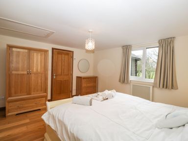 A bedroom with a bed white linens wooden wardrobe dresser and window with curtains at The Annex in Royal Wootton Bassett
