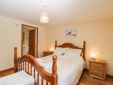 A bedroom with a wooden bed and two bedside tables with lamps at The Annex in Royal Wootton Bassett