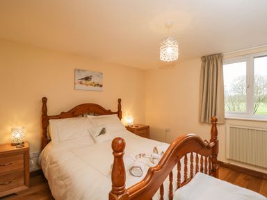 A bedroom with a wooden bed and bedside tables with lamps at The Annex in Royal Wootton Bassett