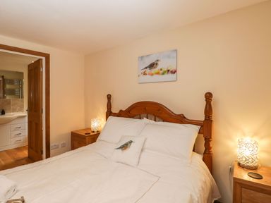 A bedroom with a wooden bed frame white bedding bedside tables and lamps at The Annex in Royal Wootton Bassett