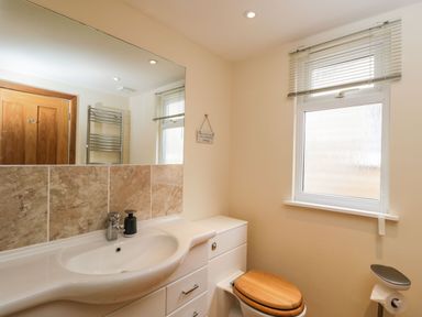 A bathroom with a sink, mirror, window with blinds, toilet with wooden seat at The Annex in Royal Wootton Bassett