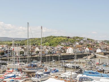 A marina with boats and yachts docked near a town with houses and green hills at The Old Byres in Washford near Watchet