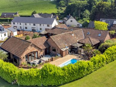 An aerial view of a property with multiple connected buildings a swimming pool and a patio area surrounded by greenery at The Old Byres in Washford near Watchet