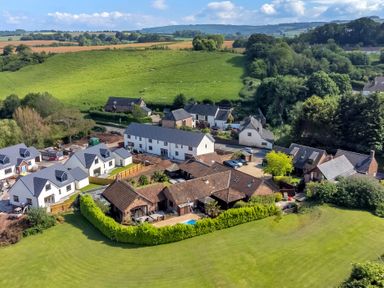 Aerial view of houses with green lawns and fields in the background at The Old Byres in Washford near Watchet
