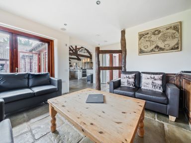 A living room with two black leather sofas a wooden coffee table and a world map on the wall at The Old Byres in Washford near Watchet