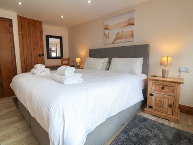 A bedroom with a large bed and towels at The Old Byres in Washford near Watchet
