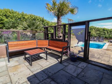 An outdoor area with seating and a pool at The Old Byres in Washford near Watchet