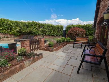 A garden with benches and paved patio at The Old Byres in Washford near Watchet