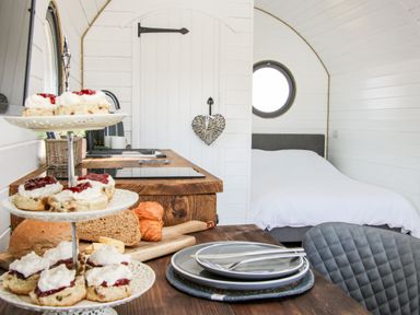A small kitchen and dining area with scones and bread next to a bed in a white wooden room at Withy Willows in Diddlebury near Ludlow