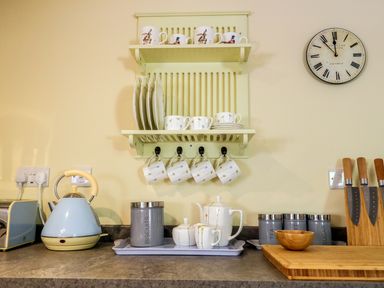 A kitchen counter with a kettle toaster plates cups canisters and knives at Woodpecker Lodge in Henley near Langport