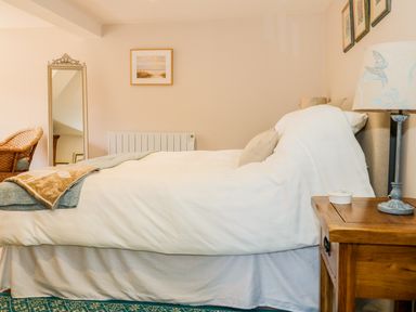 A bedroom with a double bed bedside table lamp mirror and chair at Woodpecker Lodge in Henley near Langport