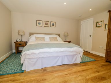 A bedroom with a double bed two bedside tables lamps and framed pictures on the walls at Woodpecker Lodge in Henley near Langport