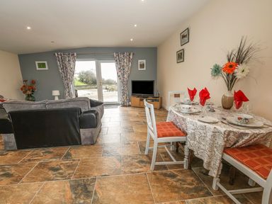 A living room with a sofa dining table set with plates and red napkins and a television at Knott Lodge in Sedbergh