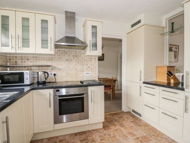 A kitchen with white cabinets black countertops stainless steel oven microwave kettle and a bread box at Dehangfa in Fairbourne
