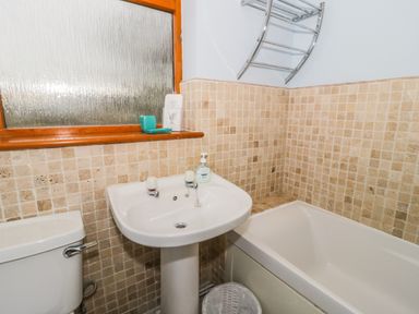 A bathroom with a bathtub sink toilet and a window at Dehangfa in Fairbourne