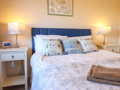 A bedroom with a bed with patterned pillows and two bedside tables with lamps at Dehangfa in Fairbourne