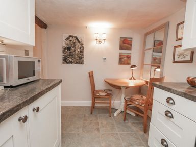 A small dining area with two wooden chairs and a round table with a lamp in a kitchen at Kirkstone Cottage in Ambleside