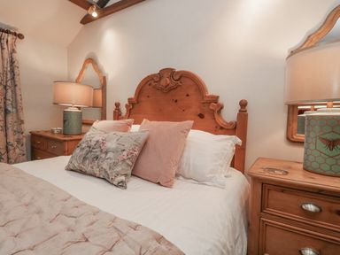A bedroom with wooden bed headboard pillows bedside tables and lamps at Kirkstone Cottage Ambleside