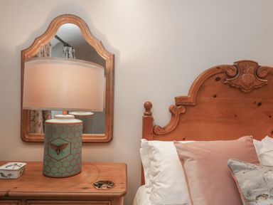 A bedside table with a lamp and a small box next to a wooden bed with pillows at Kirkstone Cottage in Ambleside
