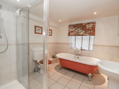 A bathroom with a walk in shower toilet with wooden seat bathtub and sink at Kirkstone Cottage in Ambleside