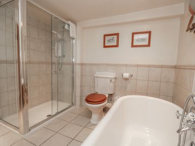 A bathroom with a shower enclosure a toilet with a wooden seat and a bathtub at Kirkstone Cottage in Ambleside