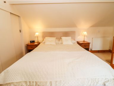 A bedroom with a double bed two bedside tables with lamps and a radiator at Elder Cottage in Mickleton near Chipping Campden