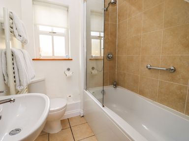 A bathroom with a bathtub shower combination sink toilet and towels at Elder Cottage in Mickleton near Chipping Campden