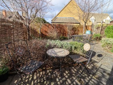 An outdoor patio with mosaic metal chairs and tables surrounded by plants at Elder Cottage in Mickleton near Chipping Campden