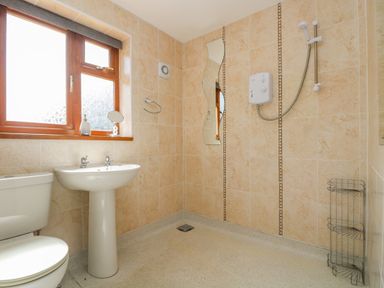 A bathroom with a toilet sink shower and window at Manege Cottage Near St Agnes