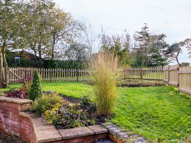 A garden with grass lawn shrubs and wooden fencing at South Lodge in Hazelbury Bryan