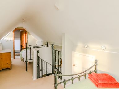 A bedroom with a metal bed frame a dresser a spiral staircase and a wooden door at South Lodge in Hazelbury Bryan