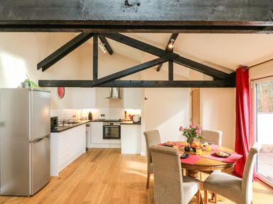 A kitchen and dining area with a round table set for breakfast and exposed wooden beams at Zeal Cottage in Crediton
