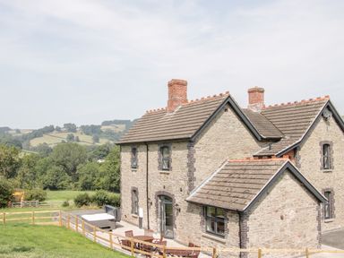 A stone house with a tiled roof and outdoor patio furniture in a rural setting at The Farm in Presteigne