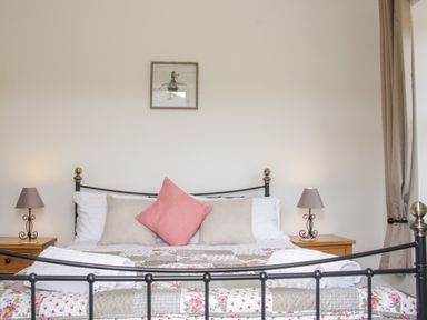 A bed with pillows and a patchwork quilt between two bedside tables with lamps in a bedroom at The Farm in Presteigne